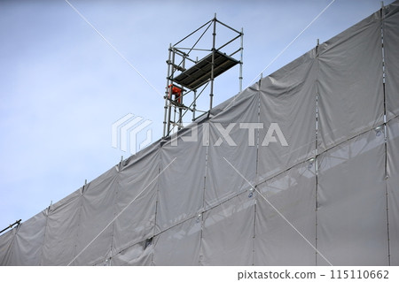 External scaffolding covered with mesh sheets (construction work) 115110662