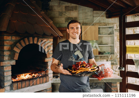 Smiling chef holding big platter with grilled vegetables 115111196