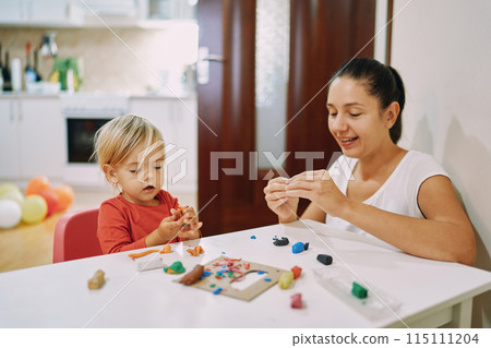 Mom and her little daughter sculpt different figures from plasticine  115111204