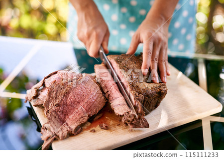 Cook cuts a juicy roast beef on a cutting board on a mirror table. Cropped 115111233