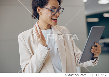 Smiling female freelancer talking with colleague via video call while standing in modern coworking 115111457