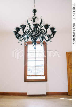 Large black chandelier hangs on the ceiling in the hall opposite the window 115111836