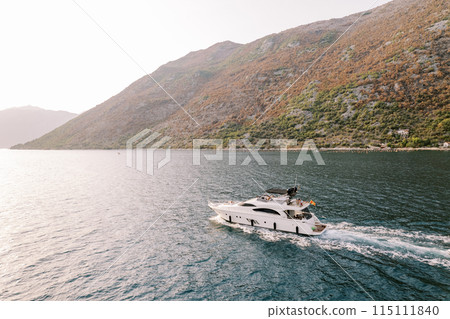 Motor single-deck yacht sails along the sea along the mountain coast 115111840