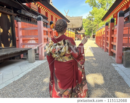 Shrine and a woman wearing a red furisode 115112088