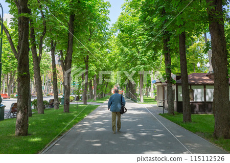 [烏克蘭] 一名男子沿著哈爾科夫市公園內的綠樹成蔭的大道行走。 115112526