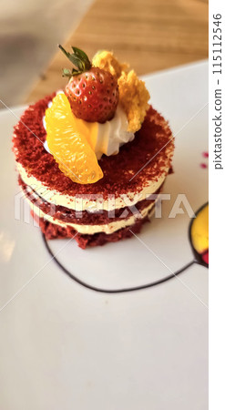 Red velvet cake, classic three layered cake from red butter sponge cakes with cream cheese frosting, with mandarin orange and candied strawberry as topping American cuisine 115112546