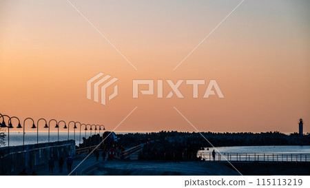 A beautiful sunset over the ocean with a lighthouse in the distance 115113219