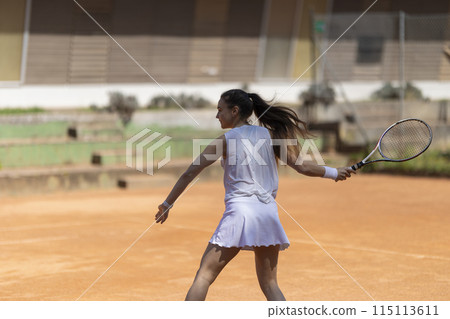 A woman is playing tennis on a clay court 115113611