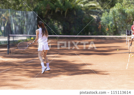 A woman is playing tennis on a clay court A woman is playing tennis on a clay court 115113614