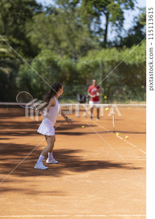 A woman is playing tennis on a clay court A woman is playing tennis on a clay court 115113615