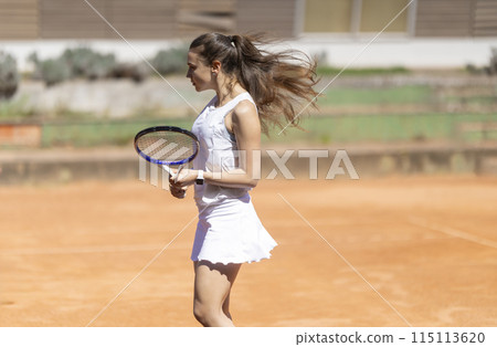 A woman in a white dress is holding a tennis racket A woman in a white dress is holding a tennis racket 115113620
