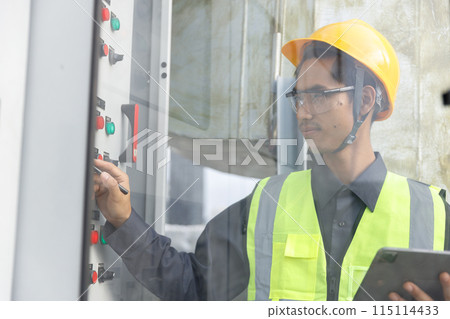 Electrical engineer man using tablet checks switchboard main Distribution Boards control panel 115114433