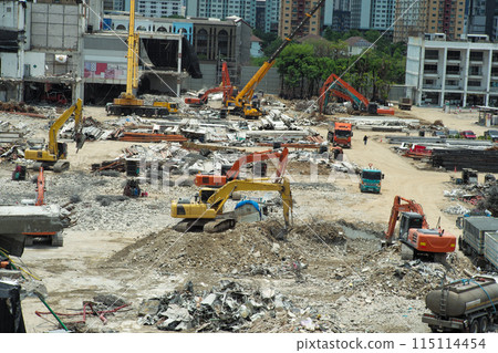 Many excavators working on the ground of the construction site while removing the salvage after the destruction of the building 115114454