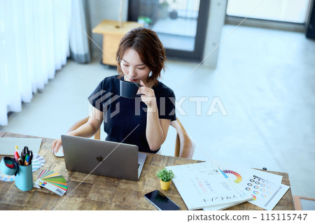 一位女設計師在家用電腦工作 115115747