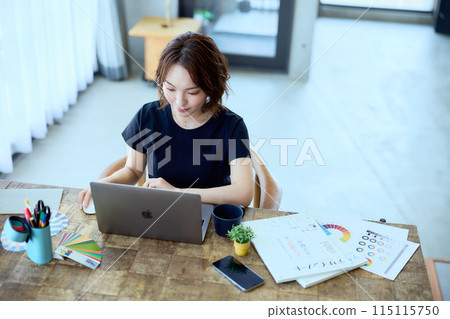 一位女設計師在家用電腦工作 115115750