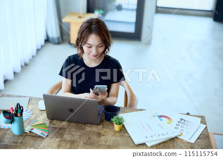 A female designer working at a computer at home 115115754