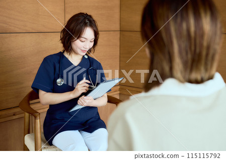 A female doctor interviewing a patient in the waiting room 115115792