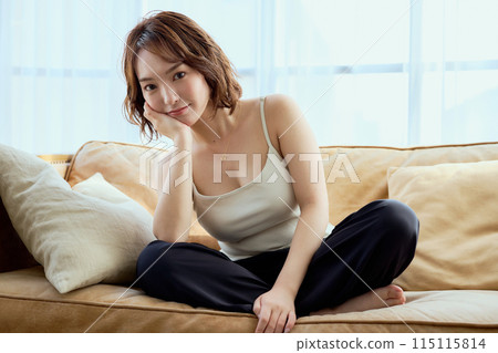 A woman sitting on a sofa and relaxing A woman sitting on a sofa and relaxing 115115814
