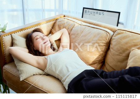 A woman lying down on a sofa A woman lying down on a sofa 115115817
