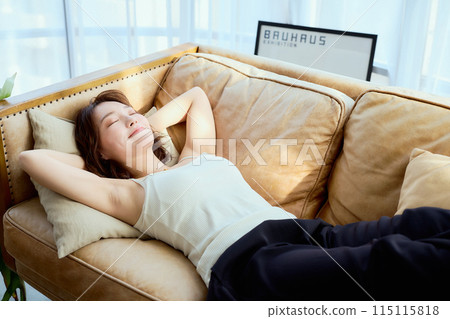 A woman lying down on a sofa 115115818