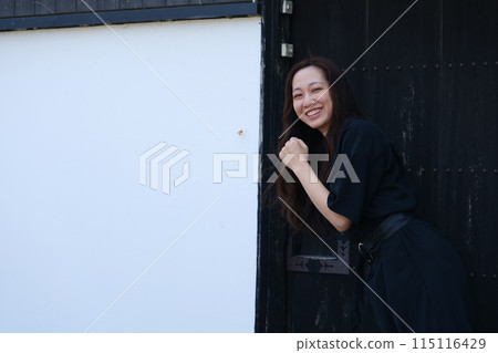 一位長髮婦女站在一座古老民宅的白牆前 一位長髮婦女站在一座古老民宅的白牆前 115116429