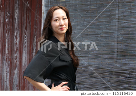 一位長髮婦女站在一座古老的民宅前 115116430