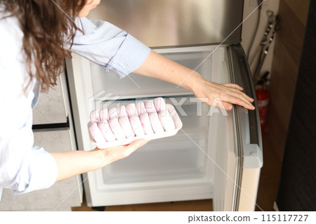 young woman takes frozen cottage cheese pancakes from the freezer on the table, frozen food 115117727