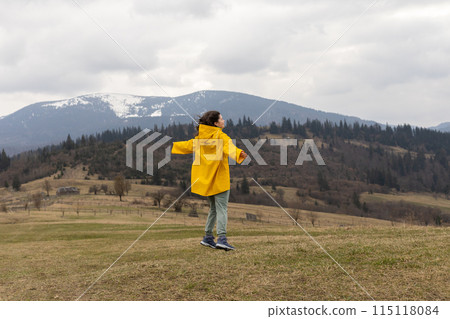 hiking, young woman in a yellow raincoat in the mountains hiking, young woman in a yellow raincoat in the mountains 115118084