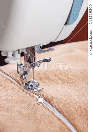 Modern sewing machine special presser foot with beige fabric and zipper, closeup 115119369
