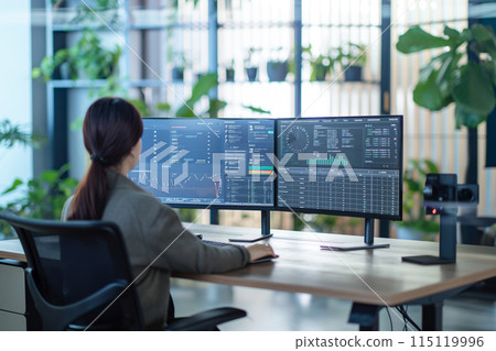 Portrait of an adult woman - data analyst at workplace working behind a large monitor, modern office design concept 115119996