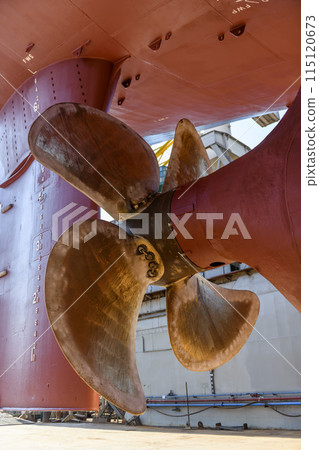 Cargo vessel in dry dock on ship repairing yard. Variable pitch propeller and rudder. Cargo vessel in dry dock on ship repairing yard. Variable pitch propeller and rudder. 115120673