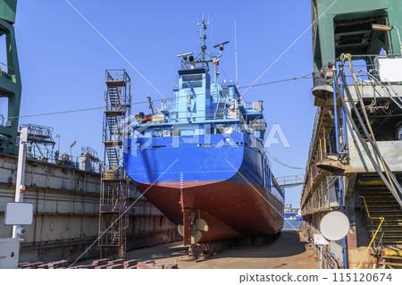 Cargo vessel in dry dock on ship repairing yard. Variable pitch propeller and rudder. 115120674