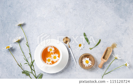 Healthy flat lay with chamomile tea in a white cup, vase, dry tea and  flowers daisy  115120724