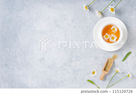 Healthy flat lay with chamomile tea in a white cup, dry tea and flowers daisy on a blue background Healthy flat lay with chamomile tea in a white cup, dry tea and flowers daisy on a blue background 115120726