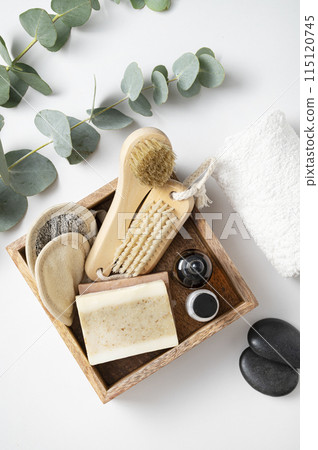 wooden box with organic cosmetics, cream, sponges, brush, soap and massage stone  115120745