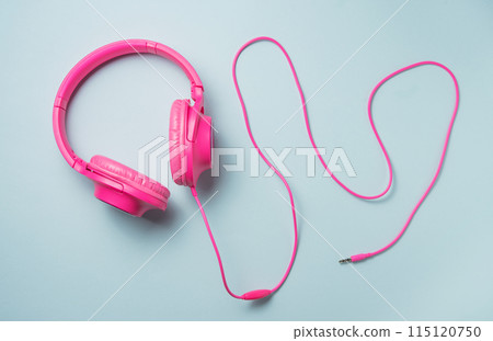 pink large headphones with a wire on a blue background. Top view pink large headphones with a wire on a blue background. Top view 115120750
