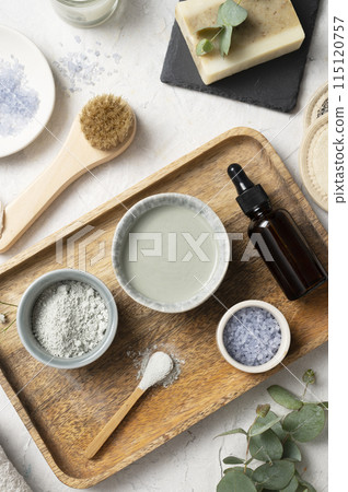 Organic cosmetic clay, brush, sea salt, oil, and eucalyptus branch on a white textured background. Organic cosmetic clay, brush, sea salt, oil, and eucalyptus branch on a white textured background. 115120757