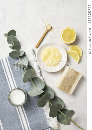 Organic yellow sea salt with lemon, soap and eucalyptus branch on a white textured background.  115120765