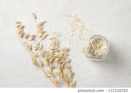 oat flakes in a jar with oats dry brunch on a white textured background. Raw and vegan product 115120783