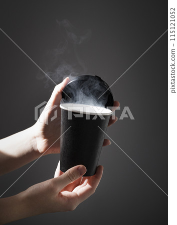 a black paper cup with aroma coffee or other drink in hands on a dark background with morning light a black paper cup with aroma coffee or other drink in hands on a dark background with morning light 115121052