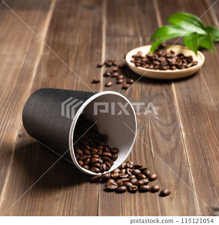 fresh aromatic coffee beans scattered on a dark wooden background from a plastic disposable cup. fresh aromatic coffee beans scattered on a dark wooden background from a plastic disposable cup. 115121054