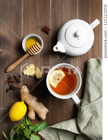Immune system booster - tea with ginger, honey, lemon, mint and spices on a dark wooden background. Immune system booster - tea with ginger, honey, lemon, mint and spices on a dark wooden background. 115121059