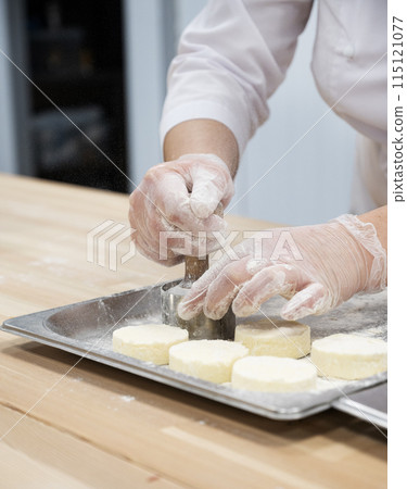 A woman makes cheesecakes by hand in production. Factory for the production of food. 115121077