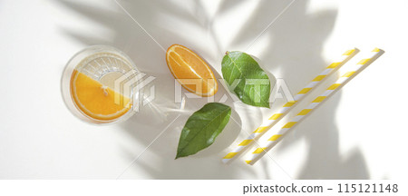 A glass of mineral water and a slice of orange on a light table with fresh juicy fruit oranges A glass of mineral water and a slice of orange on a light table with fresh juicy fruit oranges 115121148