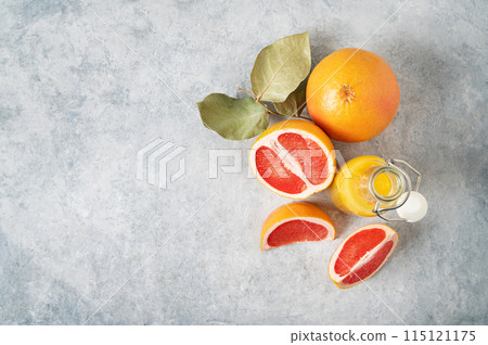 layout of juicy red grapefruits and juice in a bottle on a blue background. layout of juicy red grapefruits and juice in a bottle on a blue background. 115121175