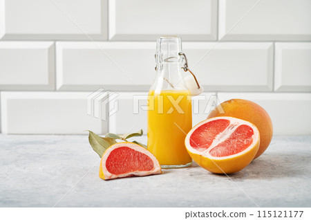 juicy grapefruit and bottle juice on a blue table on a white brick background. Front view juicy grapefruit and bottle juice on a blue table on a white brick background. Front view 115121177