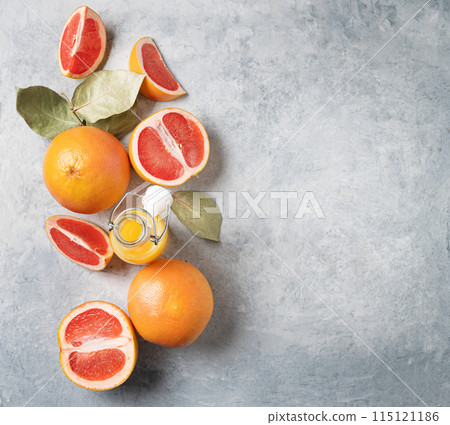 Flat lay of juicy red grapefruits and juice in a bottle on a blue background. Flat lay of juicy red grapefruits and juice in a bottle on a blue background. 115121186