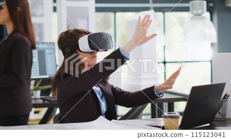 Architect designing project blueprints and plans with vr headset, using artificial intelligence to shape new property layout. Specialist working with virtual reality glasses at real estate agency. Architect designing project blueprints and plans with vr headset, using artificial intelligence to shape new property layout. Specialist working with virtual reality glasses at real estate agency. 115123041