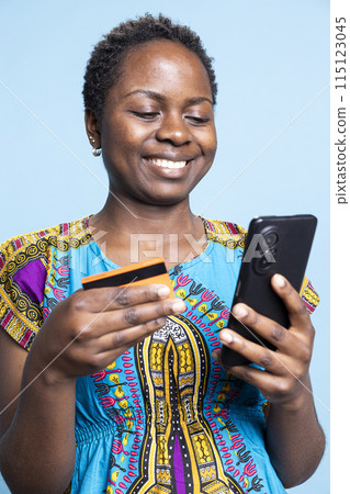 Young adult typing credit card numbers on store website, enjoying online shopping with easy pay security. African american girl making banking transaction, electronic payment. Young adult typing credit card numbers on store website, enjoying online shopping with easy pay security. African american girl making banking transaction, electronic payment. 115123045