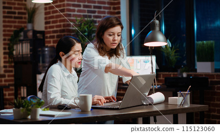 Asian staff member calling manager to her computer desk to ask for feedback on project progress. Worker in brick wall office requesting assistance from team leader during nightshift 115123060